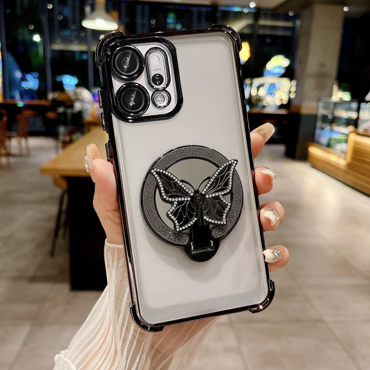 Phone case with butterfly design holder held by a hand in an indoor setting